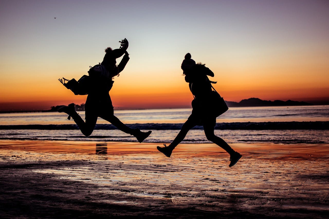Two people leaping with ahappiness on a beach.